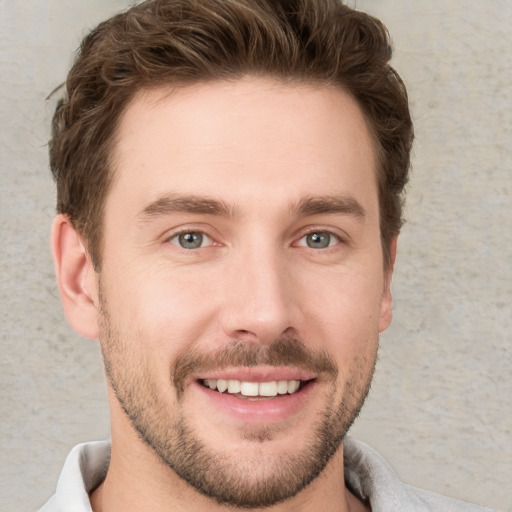 Joyful white young-adult male with short  brown hair and grey eyes