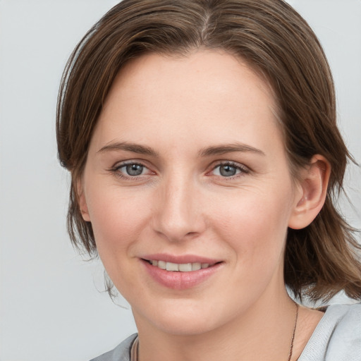 Joyful white young-adult female with medium  brown hair and grey eyes