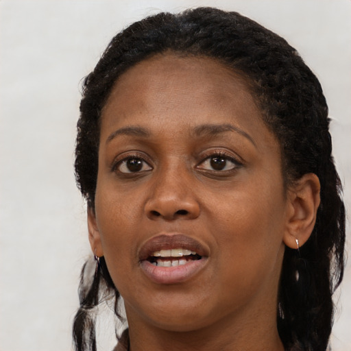 Joyful black young-adult female with long  black hair and brown eyes