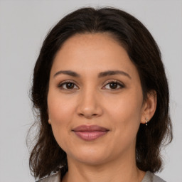 Joyful latino young-adult female with medium  brown hair and brown eyes