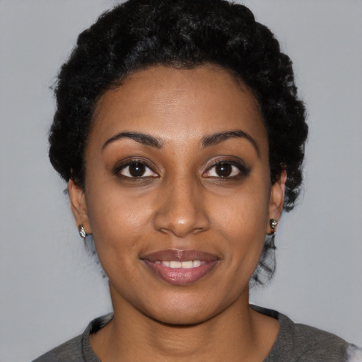 Joyful black young-adult female with short  black hair and brown eyes