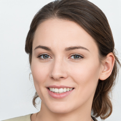 Joyful white young-adult female with medium  brown hair and grey eyes