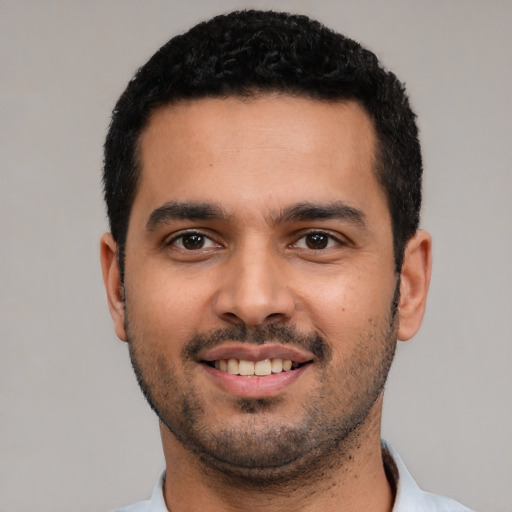 Joyful latino young-adult male with short  black hair and brown eyes