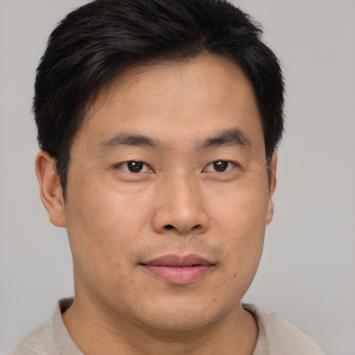 Joyful asian young-adult male with short  brown hair and brown eyes