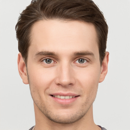 Joyful white young-adult male with short  brown hair and grey eyes