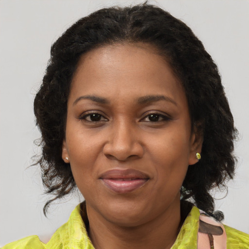 Joyful black adult female with long  brown hair and brown eyes