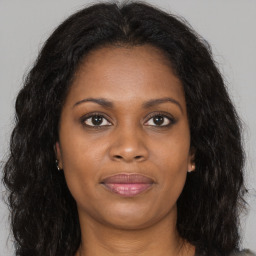 Joyful black young-adult female with long  brown hair and brown eyes