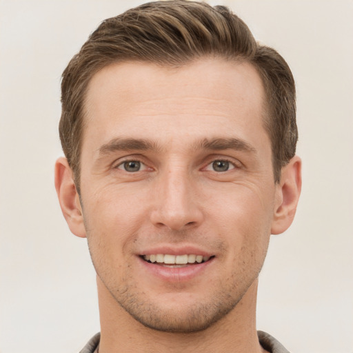 Joyful white young-adult male with short  brown hair and grey eyes