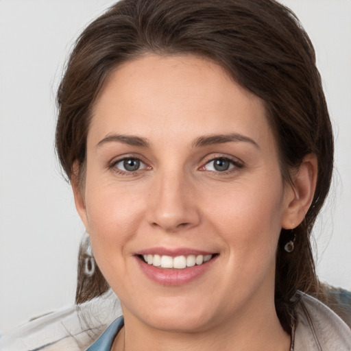 Joyful white young-adult female with medium  brown hair and grey eyes