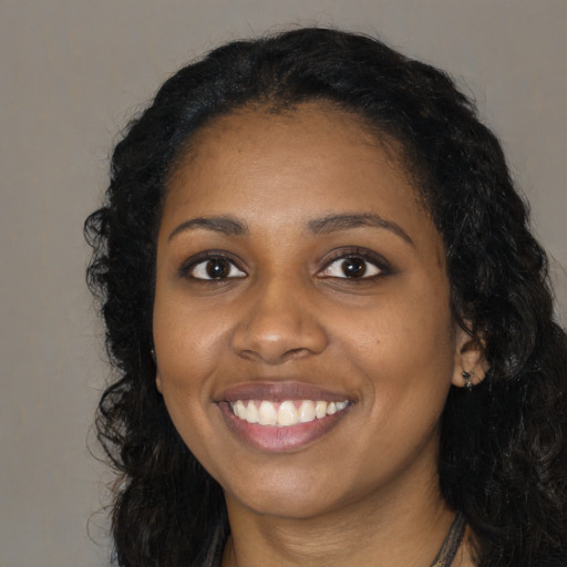 Joyful black young-adult female with long  black hair and brown eyes