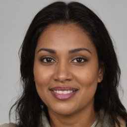 Joyful black young-adult female with long  brown hair and brown eyes