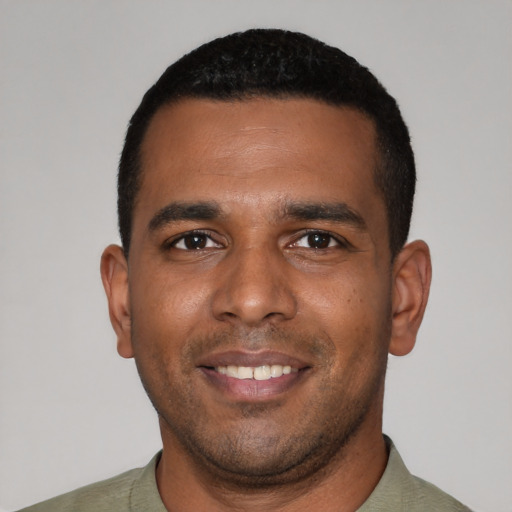 Joyful black young-adult male with short  black hair and brown eyes