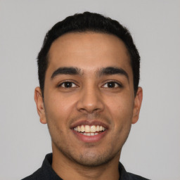 Joyful latino young-adult male with short  black hair and brown eyes