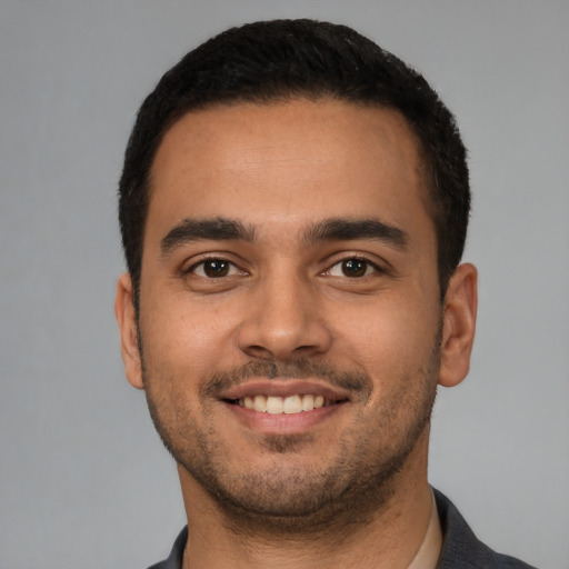 Joyful latino young-adult male with short  black hair and brown eyes