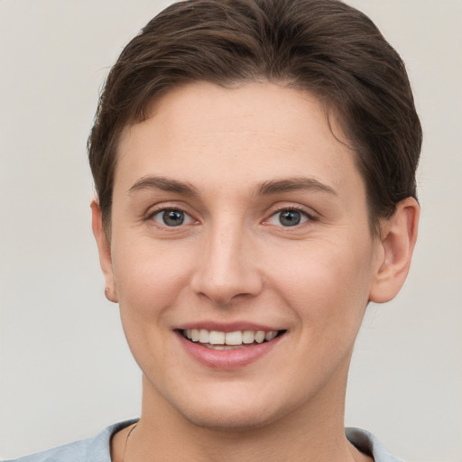 Joyful white young-adult female with short  brown hair and grey eyes