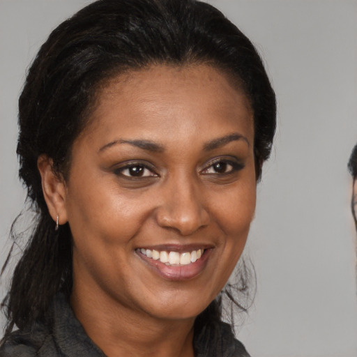Joyful black adult female with medium  brown hair and brown eyes