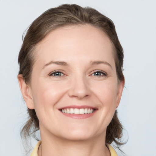 Joyful white young-adult female with medium  brown hair and grey eyes