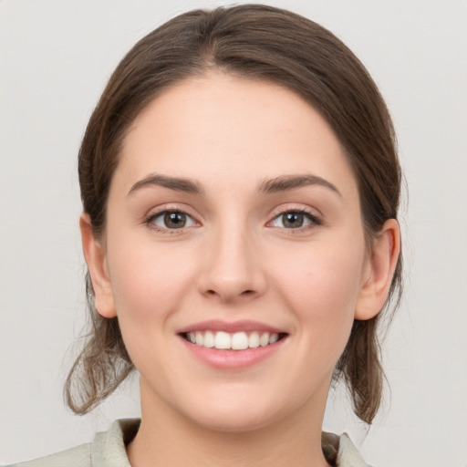 Joyful white young-adult female with medium  brown hair and grey eyes