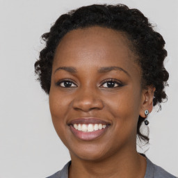 Joyful black young-adult female with long  brown hair and brown eyes