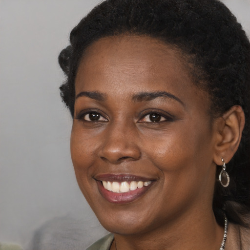 Joyful black young-adult female with long  brown hair and brown eyes