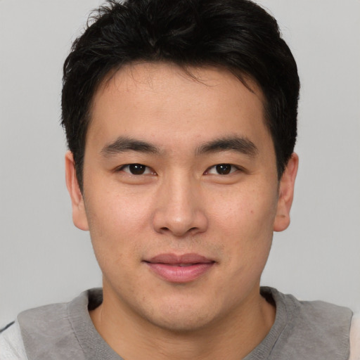 Joyful asian young-adult male with short  brown hair and brown eyes