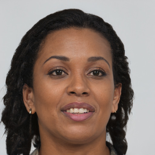 Joyful black young-adult female with long  brown hair and brown eyes