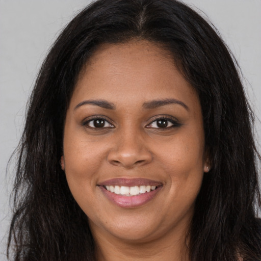 Joyful black young-adult female with long  brown hair and brown eyes