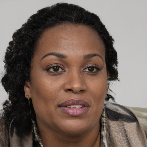 Joyful black adult female with long  brown hair and brown eyes