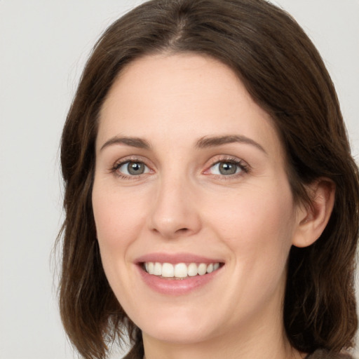 Joyful white young-adult female with medium  brown hair and grey eyes