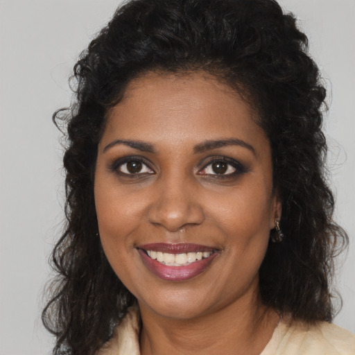Joyful black young-adult female with long  brown hair and brown eyes