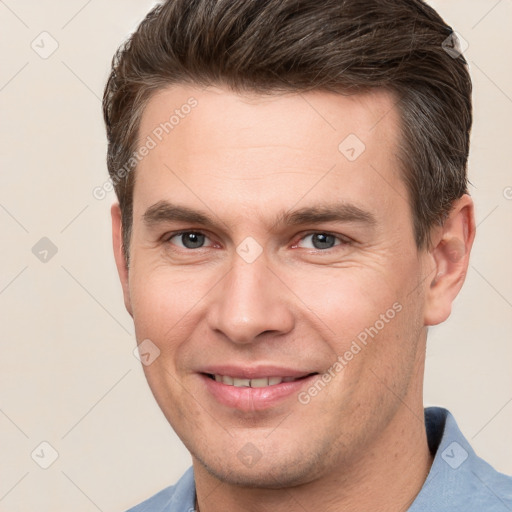 Joyful white young-adult male with short  brown hair and grey eyes