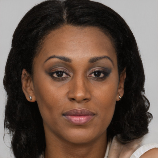Joyful black young-adult female with long  brown hair and brown eyes