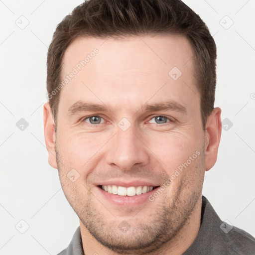 Joyful white young-adult male with short  brown hair and grey eyes