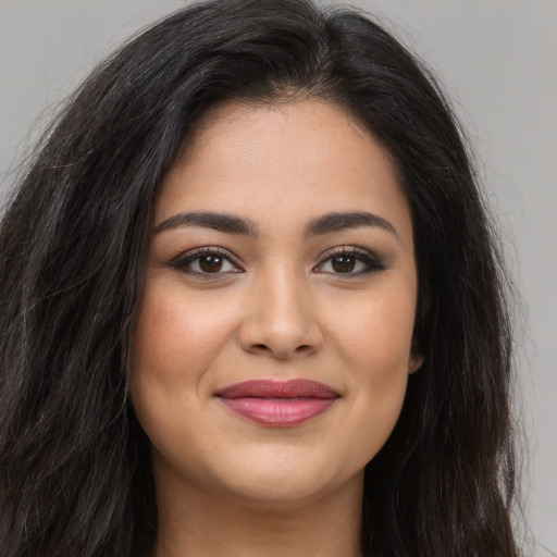Joyful latino young-adult female with long  brown hair and brown eyes