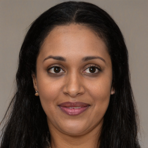 Joyful black young-adult female with long  black hair and brown eyes