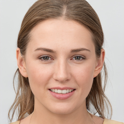 Joyful white young-adult female with medium  brown hair and grey eyes