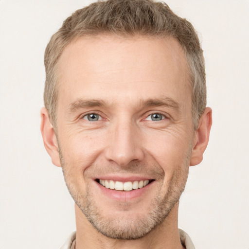 Joyful white young-adult male with short  brown hair and grey eyes