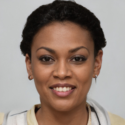 Joyful black young-adult female with short  black hair and brown eyes
