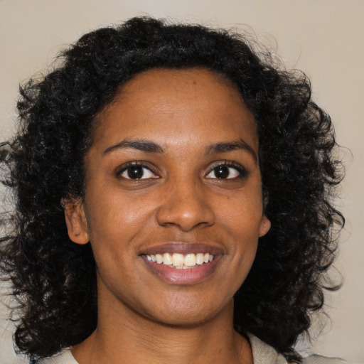 Joyful black young-adult female with long  black hair and brown eyes