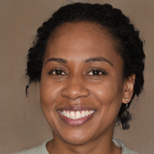 Joyful black adult female with long  brown hair and brown eyes