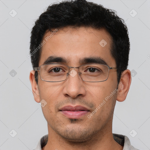 Joyful latino young-adult male with short  black hair and brown eyes