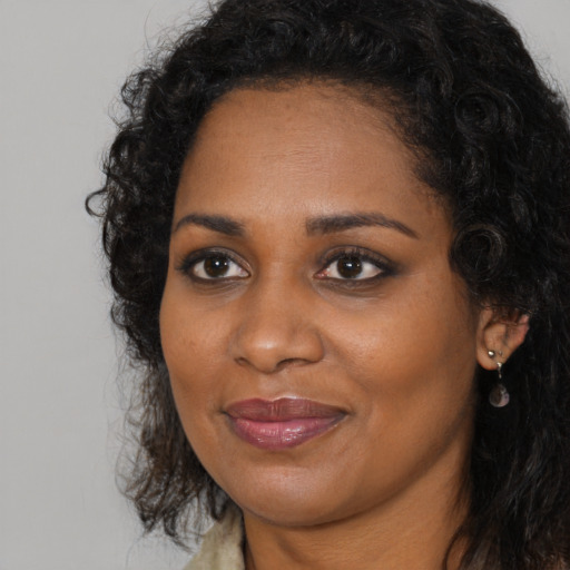 Joyful black young-adult female with long  brown hair and brown eyes