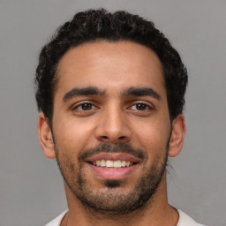 Joyful latino young-adult male with short  brown hair and brown eyes