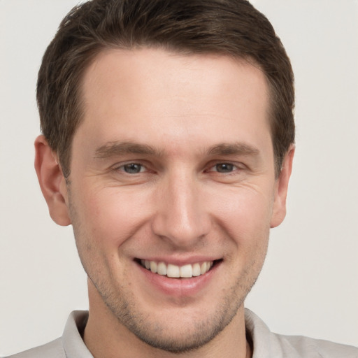 Joyful white young-adult male with short  brown hair and grey eyes