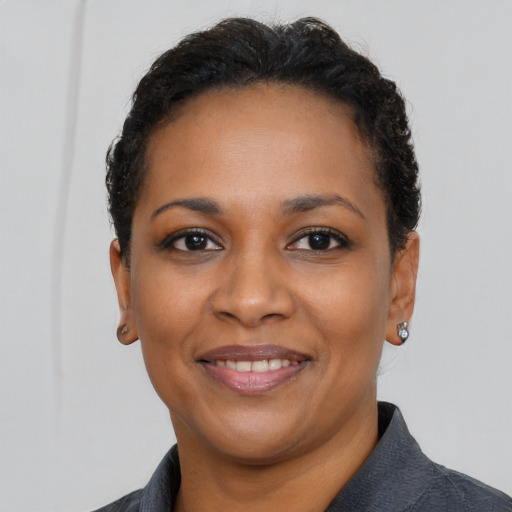 Joyful black young-adult female with short  black hair and brown eyes