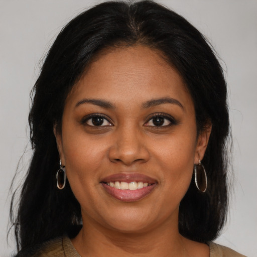 Joyful black young-adult female with long  brown hair and brown eyes