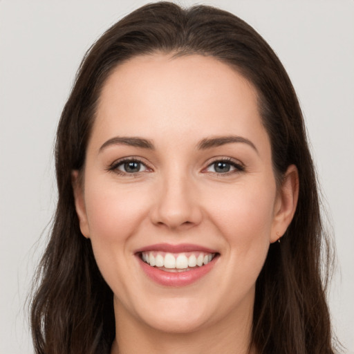 Joyful white young-adult female with long  brown hair and brown eyes