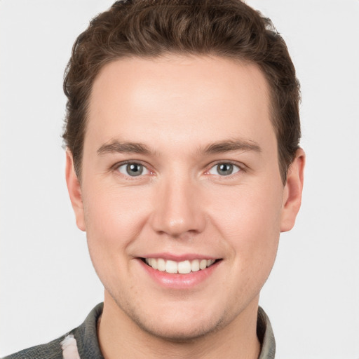 Joyful white young-adult male with short  brown hair and grey eyes