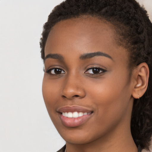 Joyful black young-adult female with long  brown hair and brown eyes