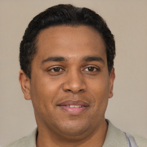 Joyful black young-adult male with short  brown hair and brown eyes